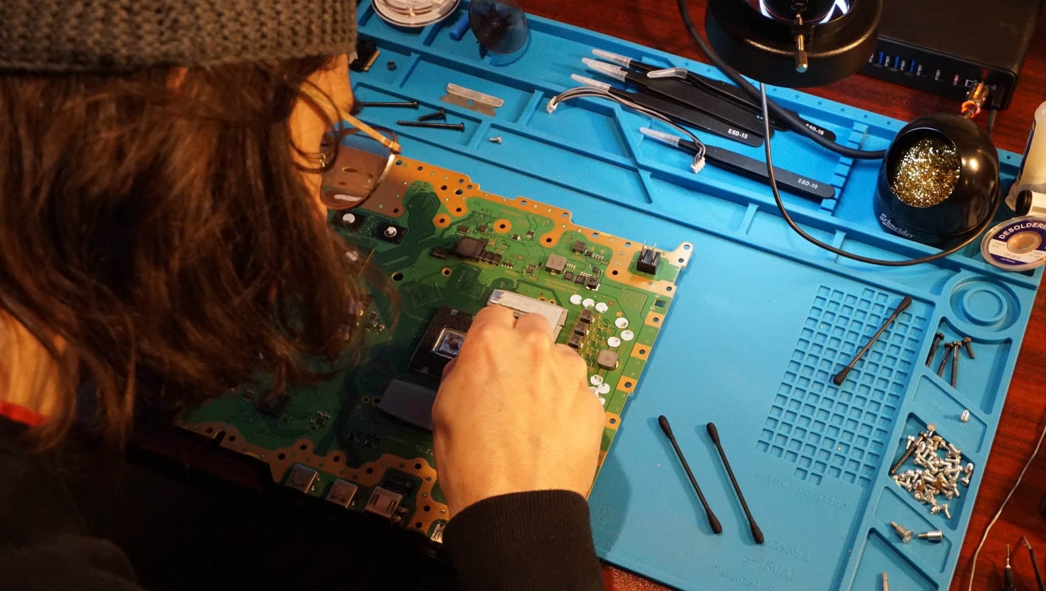 Technician working on a console motherboard at the MPR workbench